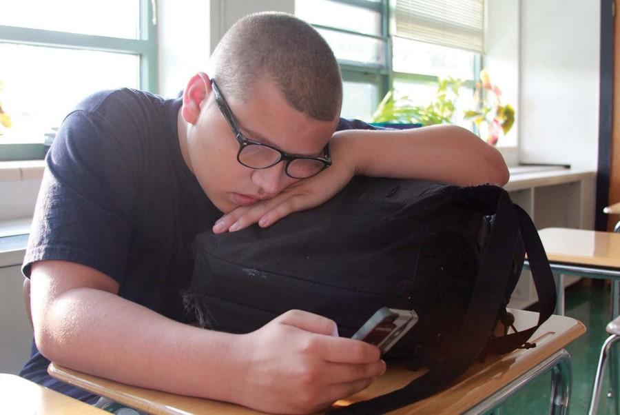Resting on his backpack, senior Xavien Weseman-Wisdom finishes homework, reading chapters from War of the Worlds before school starts on Sept. 9.