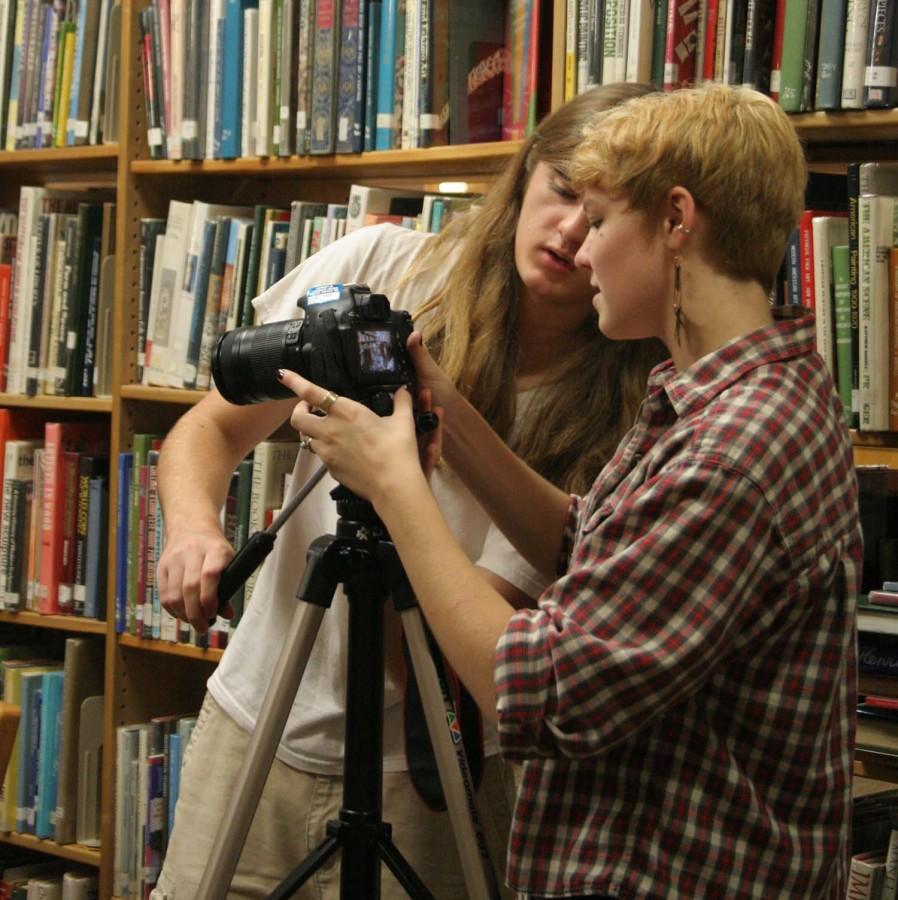 Senior Clara Cobb and Jack Rischer film the homecoming video in the library.