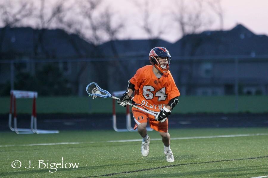 Running down the field, junior Coulter Strauss plays lacrosse with his Olathe East team. He has played on that school’s varsity team since his freshman year. Photo courtesy of J. Bigelow