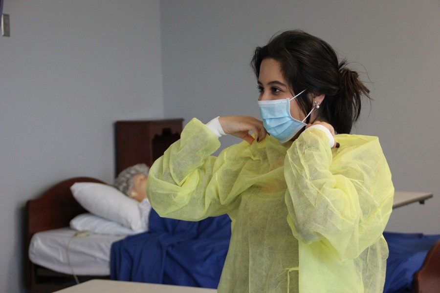 Senior Alex Aguilar puts on her scrubs for her CNA certification class at the College and Career Center last week. We are working on how to prepare ourselves to work with our patients at the nursing home,  she said.