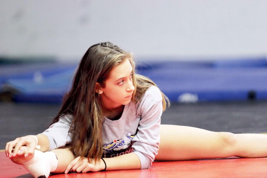 Freshman Eden Kingery stretches out before a practice. She was one of the three freshmen on the varsity gymnastics squad and said  she “know[s] all of the girls from LGA (Lawrence Gynamstics Academy).”