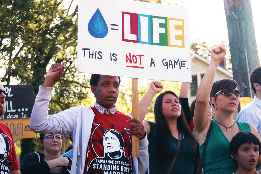 Not a game — With their fist up, sophomore Baxter Spielman  holds a sign reading “THIS IS NOT A GAME,” at the Standing for Standing Rock March in Lawrence on Sept. 30. “I researched [the issue] and felt like displacing people was inhumane,” Spielman said. “I feel like people should be able to stay where their roots are.” 