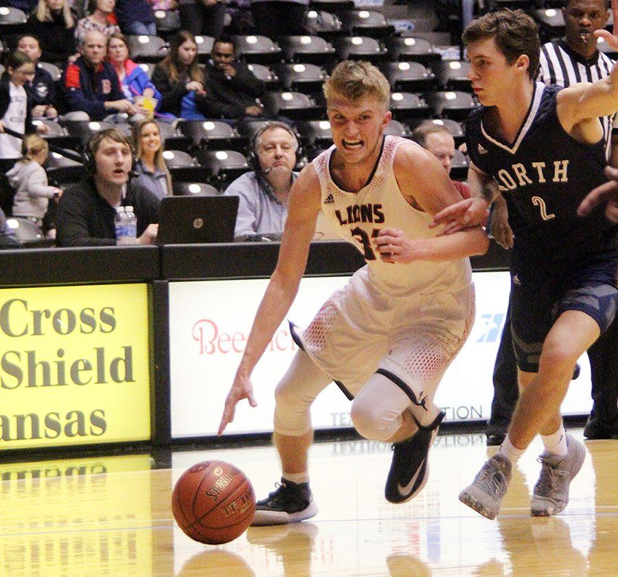Senior Jackson Mallory drives the ball down the court during the first half of the LHS v. Blue Valley North state semifinals game Friday night. Mallory had eight points in the first half.