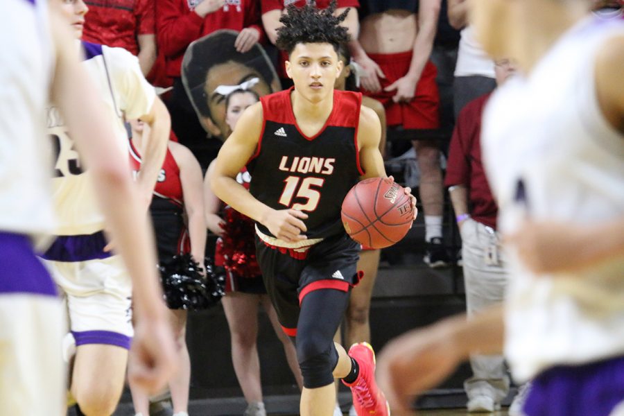 Junior Trey Quartlebaum takes the ball down the court with the student section standing behind him during the first half of the state quarterfinal game against Blue Valley Northwest. The Huskeys led from the start, knocking the Lions out of the tournament.