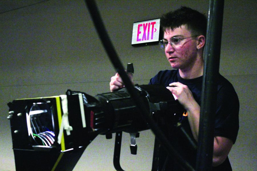 Adjusting — Senior Liam Romano runs the lights in his position at the Lawrence Arts Center.
