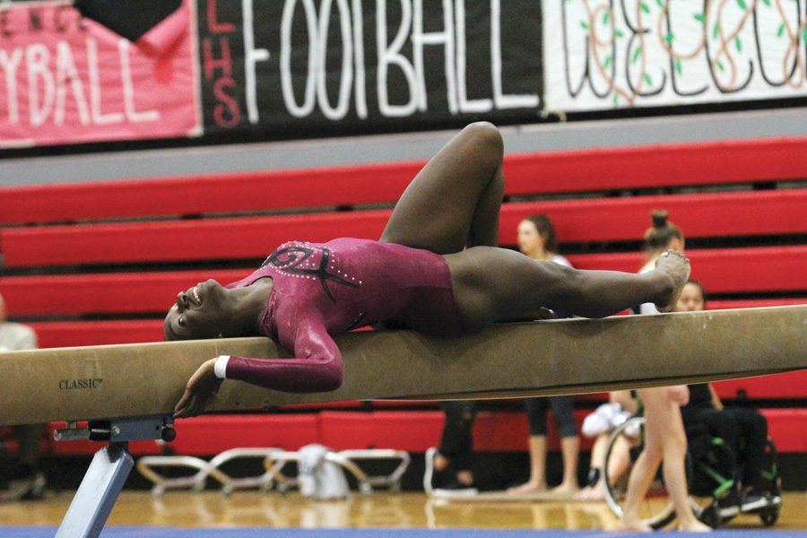 Junior Abby Afful smiles while doing a routine on the balance beam. The Lions gymnastics team placed first at the Lawrence High invitational on Sept. 27. “The most challenging part of gymnastics is trying to get new skills on bars.” Afful said. “It’s scary jumping from bar to bar and having to think about how if I have a little bit of bad technique, I could fall and break a bone.”
