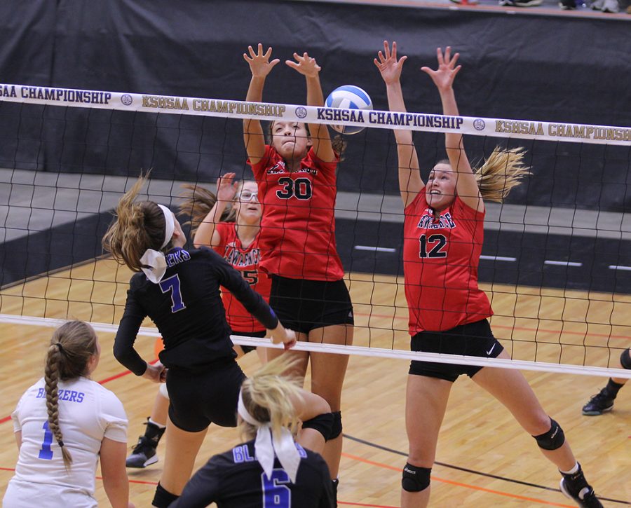 Seniors Abby Monroe and Brooke Wroten reach for the ball during the state volleyball tournament on Friday in Salina. The Lions beat Gardner-Edgerton in two sets.