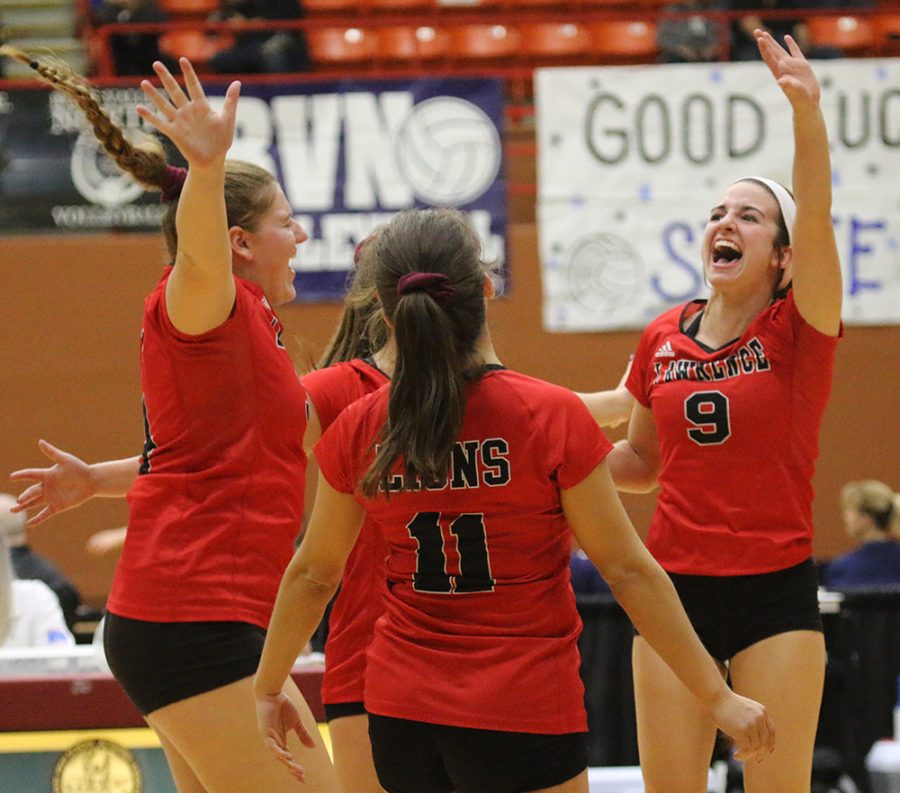 Hannah Stewart leaps with other members of the LHS volleyball team as they near the end of their second set against Blue Valley High School. The Lions dominated the first day of play at the state tournament in Salina.