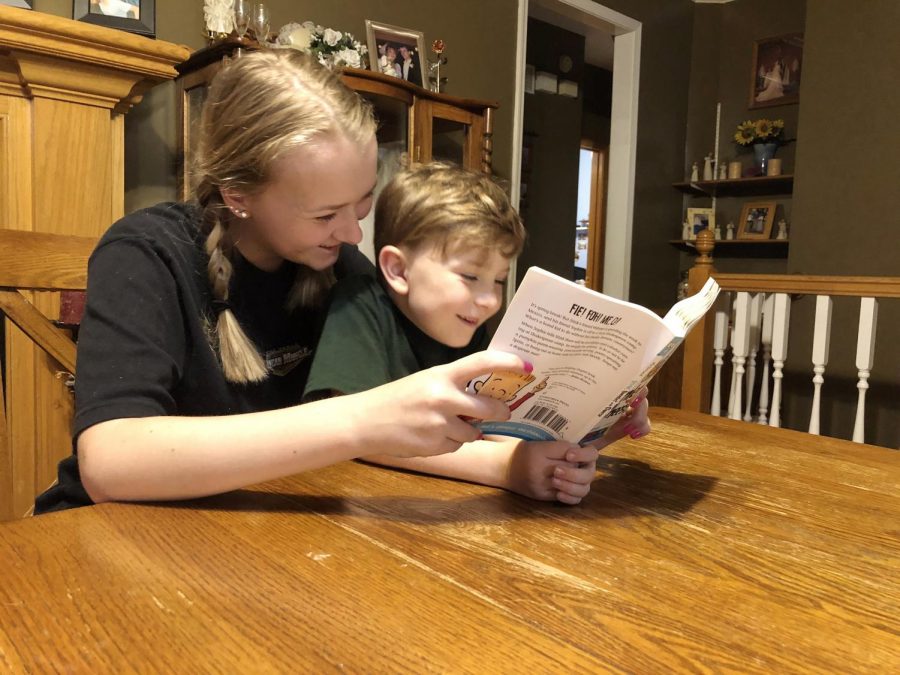 Helping with her brother Liam, sophomore Kenna McNally reads Hamlet and Cheese. While her parents work, McNally is one of many high school students who is also helping care for younger siblings.