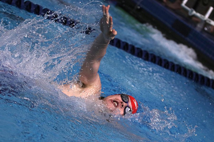 Breaking the surface, senior Jake Signor competes in the 100 backstroke during prelims at the Sunflower League meet on Feb. 7. “League was pretty intimidating but that was all a part of the experience,” Signor said. 