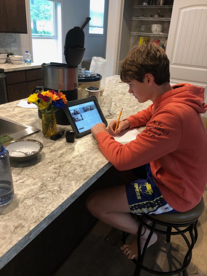 Freshman Samuel Cohen takes notes during online class in his kitchen. Students learn from home because of the ongoing coronavirus pandemic