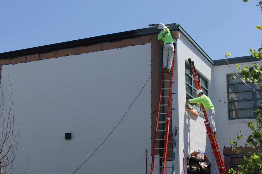 Painters paint the courtyard walls white at LHS in preparation for a large mural, which will be painted this summer.