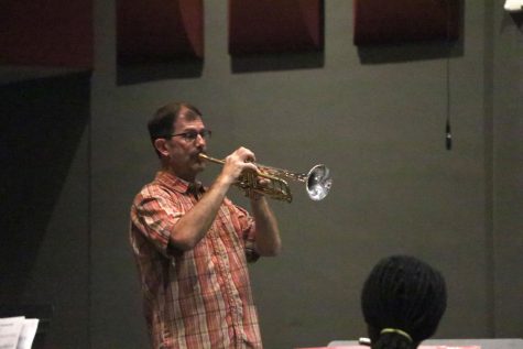 Band director Mike Jones plays trumpet while teaching the concert band during rehearsal.