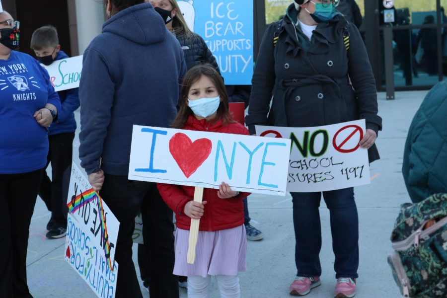 A young protestor at Save Our School 497’s demonstration outside the district offices on Monday, January 24th, stands holding a sign that reads, “I [love] NYE.”