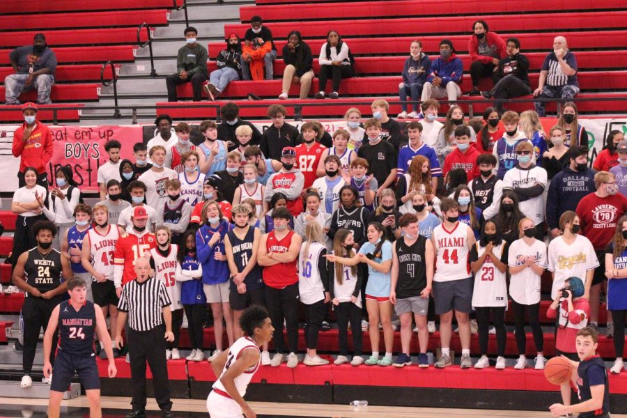 A packed student section looks on as sophomore Zaxton King defends a Manhattan player in the opening game of the season on December 4. The Lions defeated MHS 65-55. 