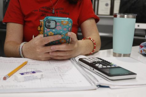 Avoiding her math homework, a student scrolls on her phone during class.