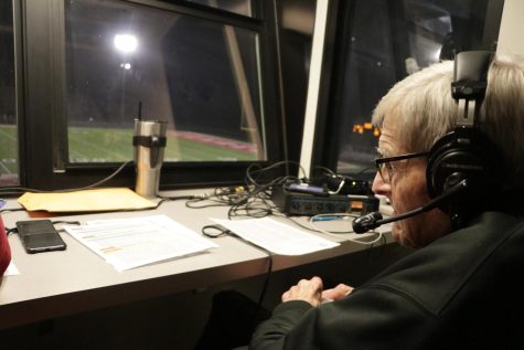 Radio announcer Hank Booth observes the field from the press box during the senior night game against Shawnee Mission West. 