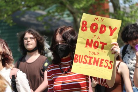 Junior Gabriel Spray holds a sign reading MY BODY IS NOT YOUR BUSINESS at the May 17 student walkout. 