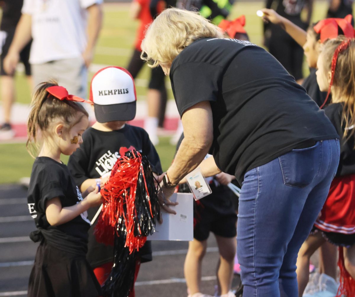 Junior Wedd hands out flash lights to the Little Lions participants in preparation for the playing of Sweet Caroline by the band at the home football game on Sept. 15.